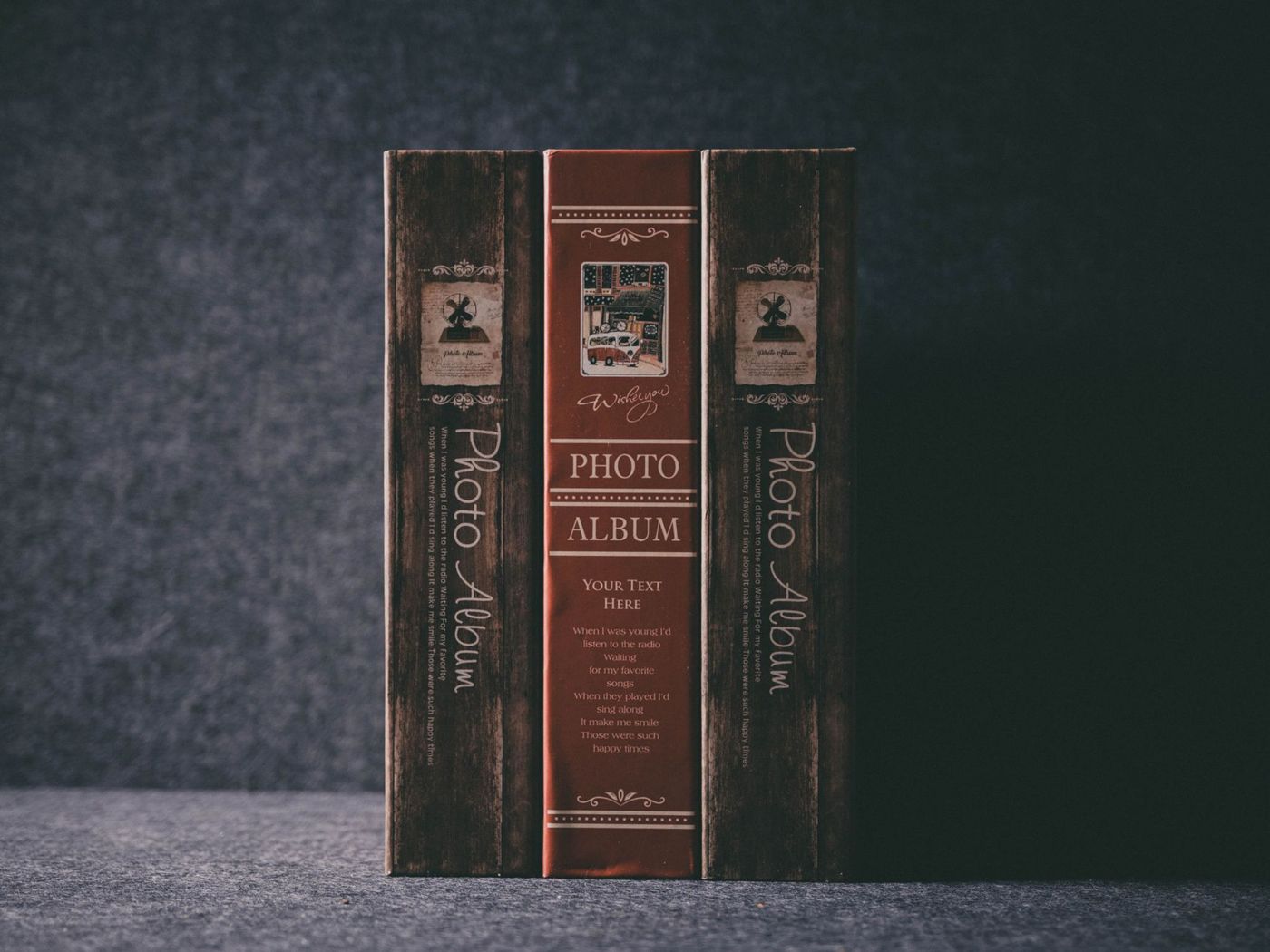 Drie fotoalbums rechtop naast elkaar, met de rug naar voren, voor een donkergrijze achtergrond