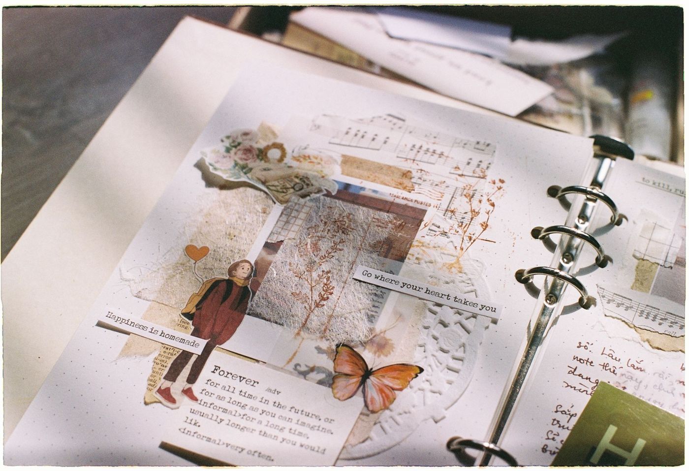 Journalpagina in een ringband met een collage van bladmuziek, bloemen, een figuurtje, een vlinder en woordstrookjes