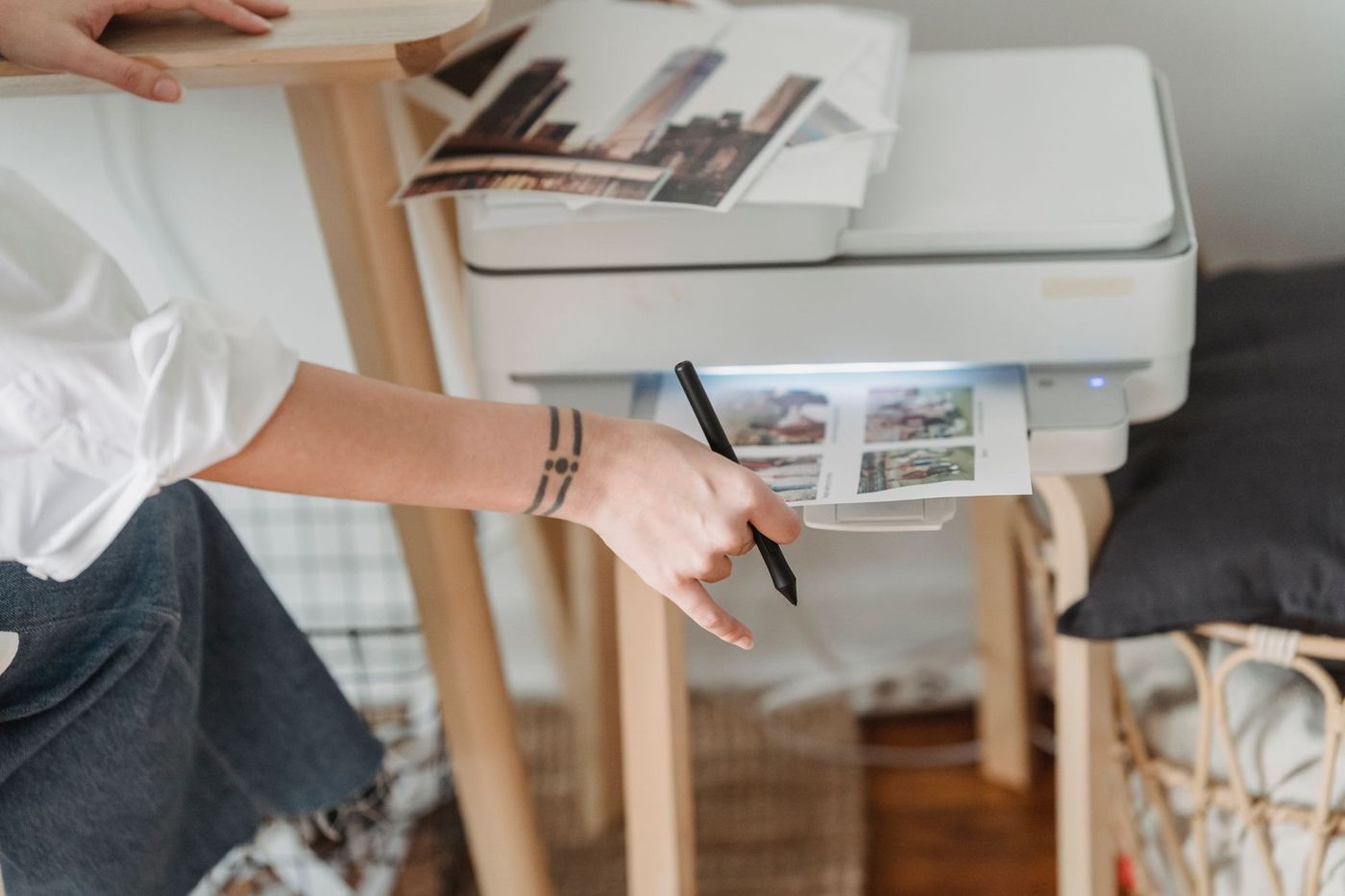 Een hand met een pen houdt een print met vier foto's vast die uit een witte printer komt