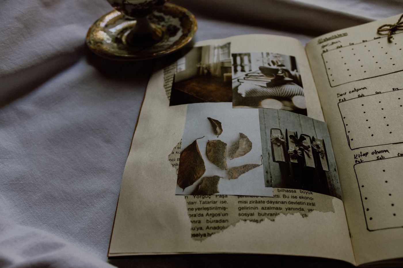 Opengeslagen journal met vier ingeplakte foto's en een gescheurde krantenrand, links een kopje op een schoteltje
