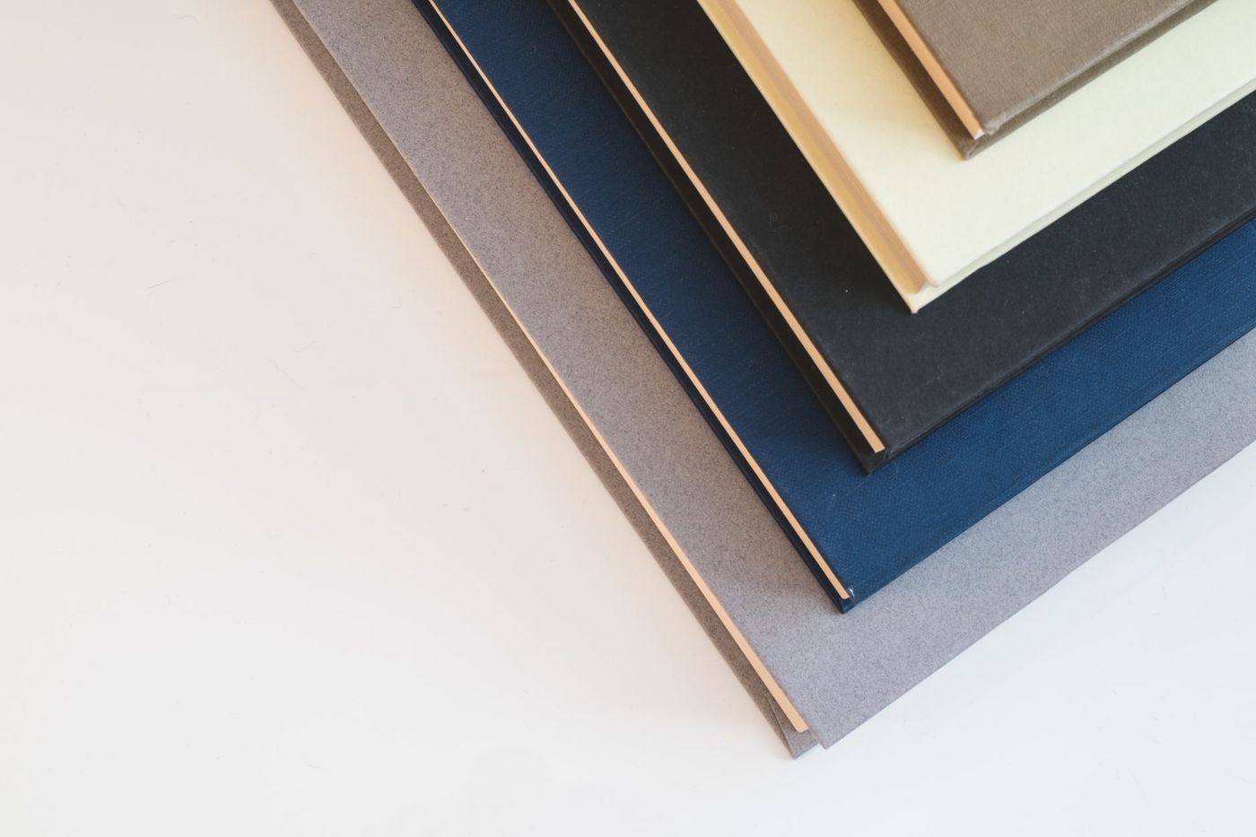 Stapel gebonden boeken met stoffen kaft in grijs, blauw, zwart en crème, van boven gezien