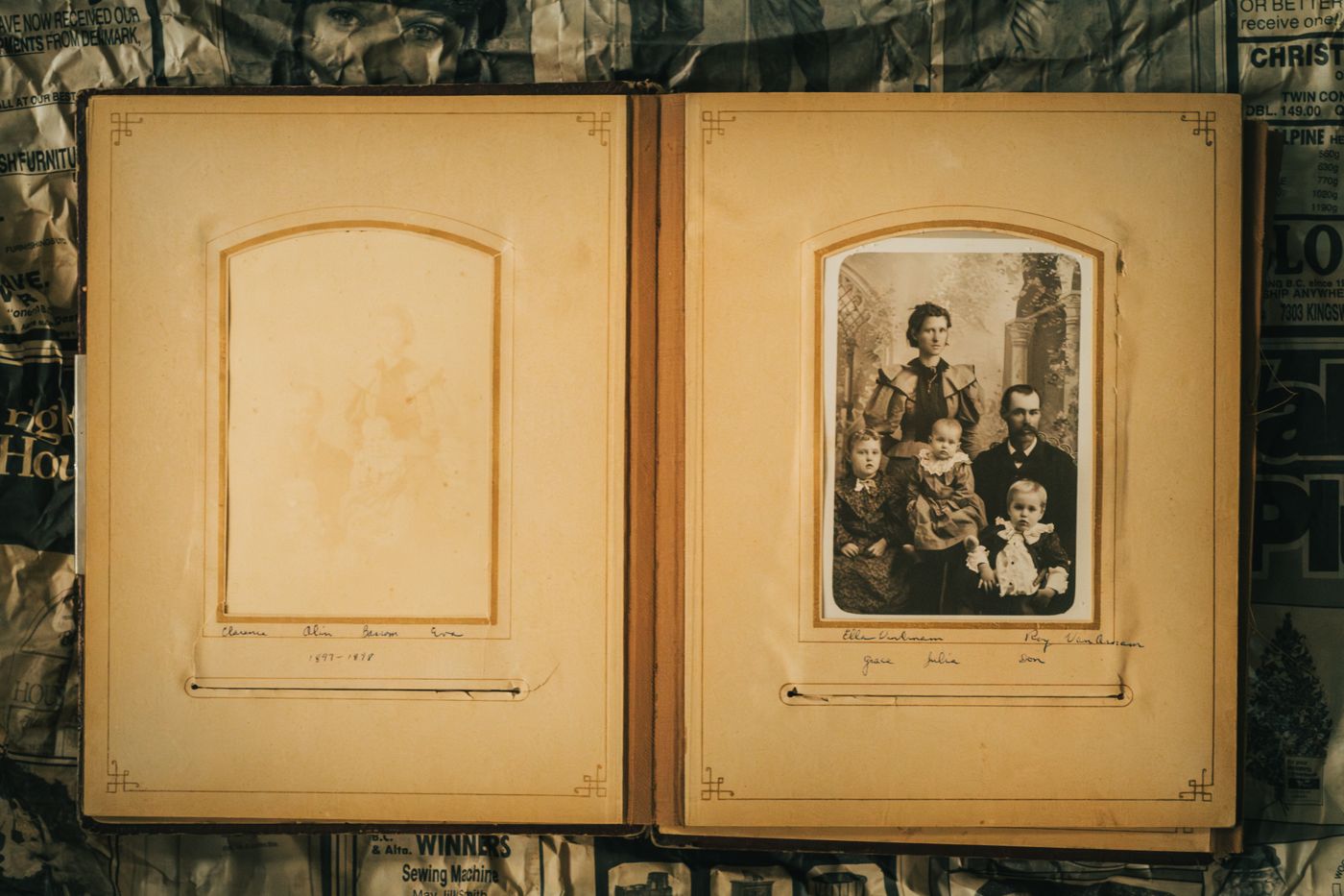 Opengeslagen oud fotoalbum: links een vergeeld, bijna weggevaagd portret, rechts een sepiafoto van een gezin